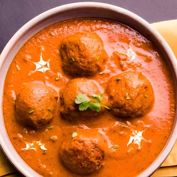 Tandoor Indian Cuisine's Malai Kofta, featuring five kofta balls in a rich orange gravy, garnished with cilantro.